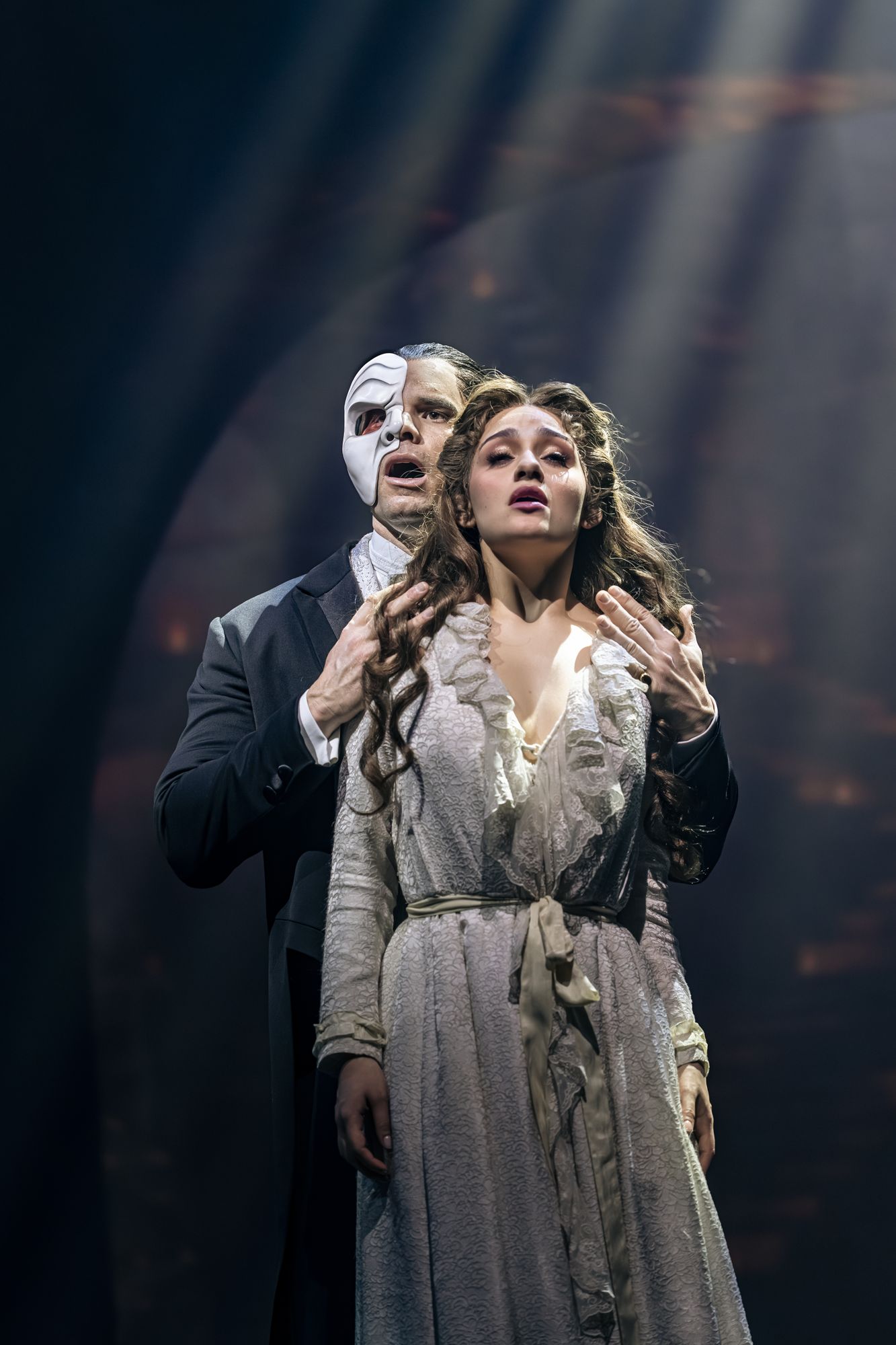 The Phantom and Christine Daaé lit by shafts of light on stage