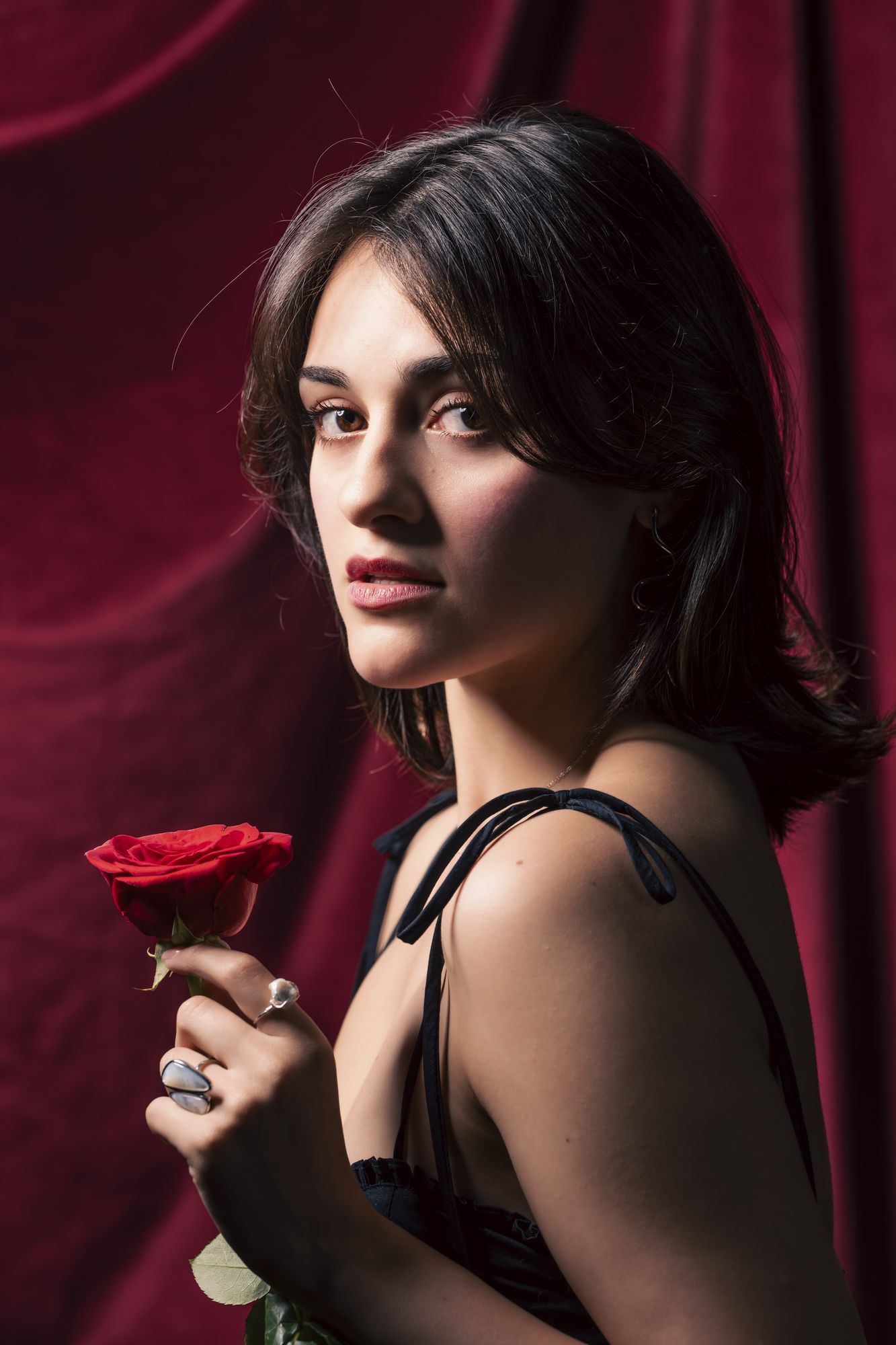 Looking over one shoulder holding a red rose