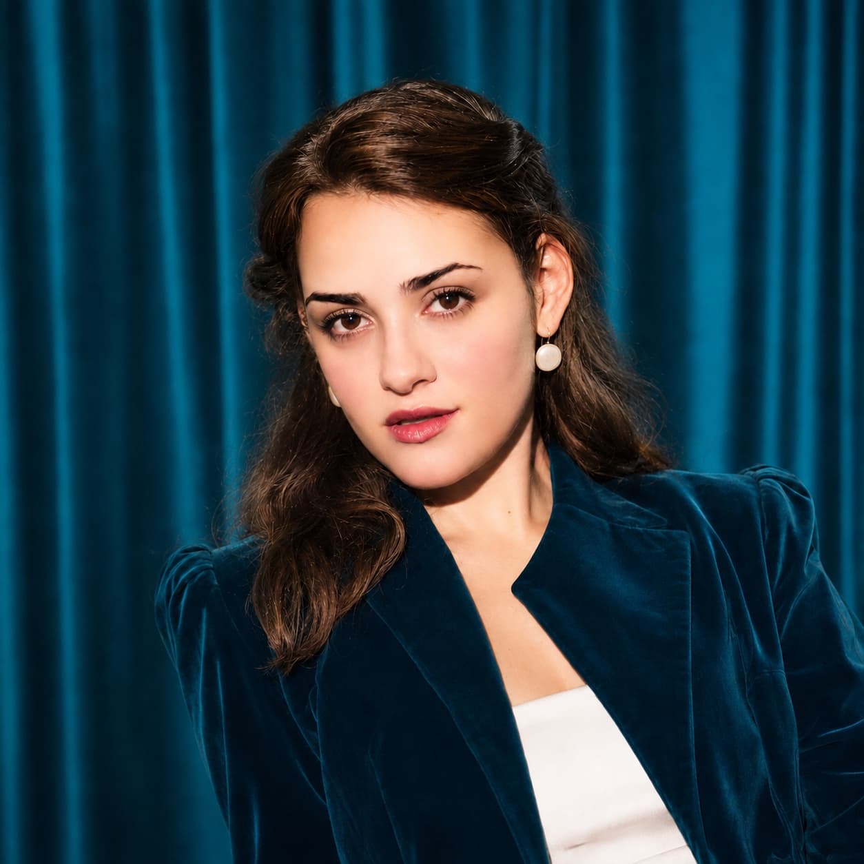 Lina de la Peña in a blue velvet jacket against a blue curtain