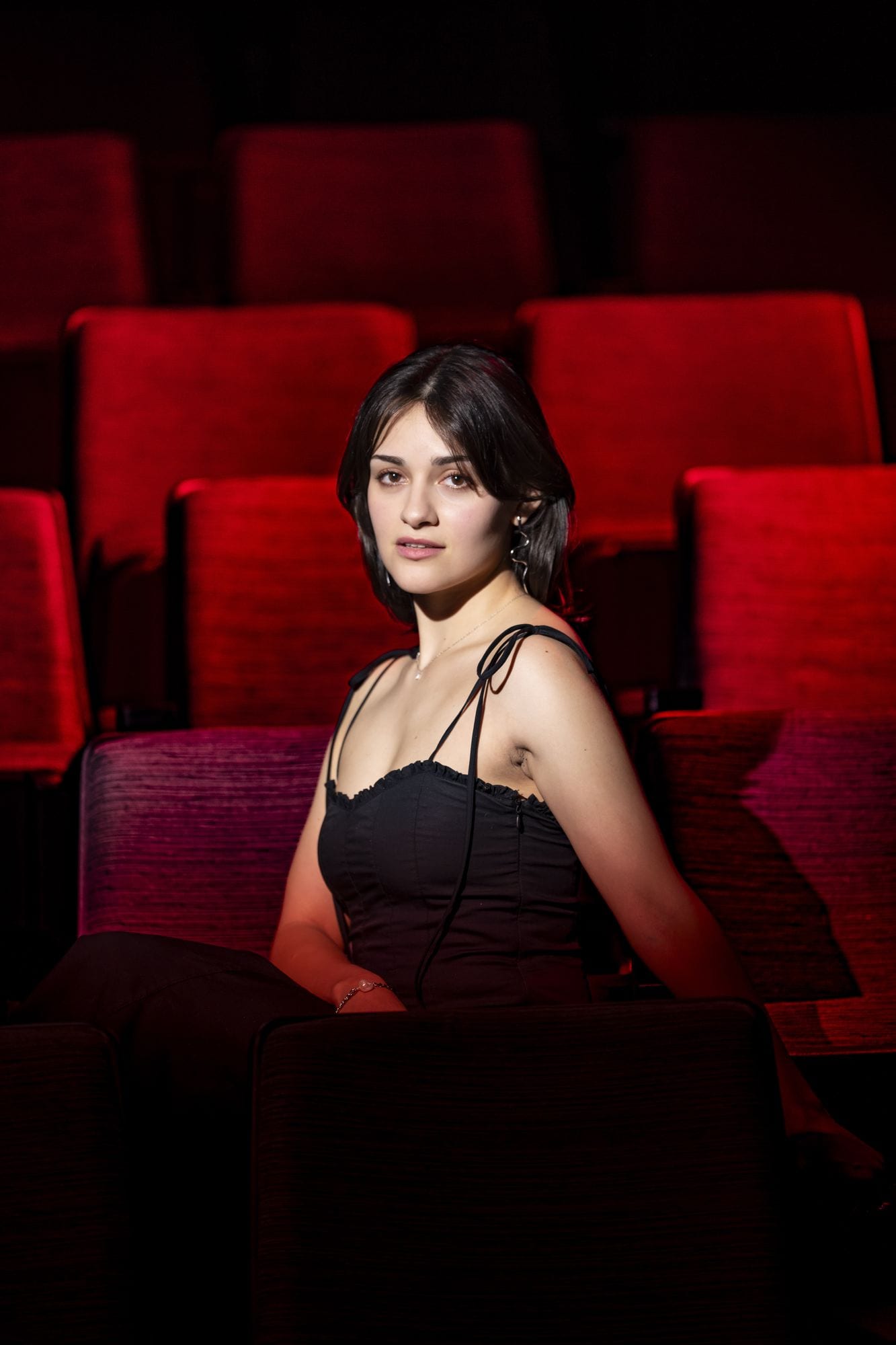 Seated among the red velvet seats of an empty theatre